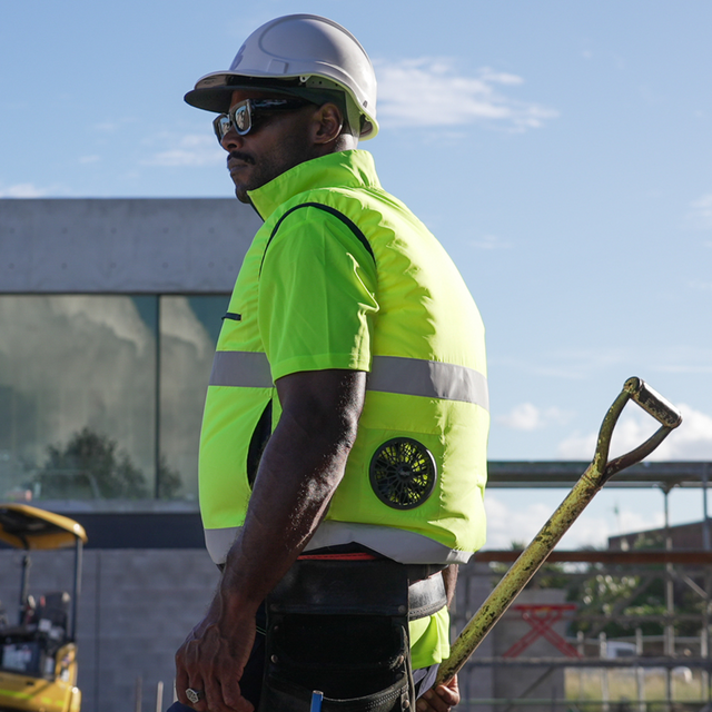 Person wearing a high-visibility fan cooled ac wear cooling air conditioned jacket and hard hat on a construction site