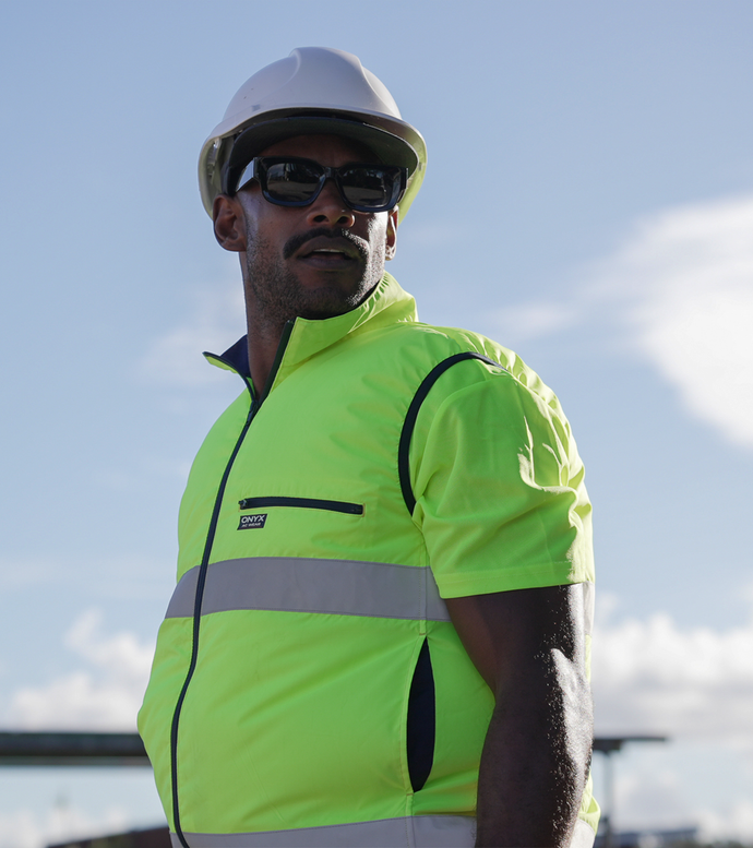 Person wearing a high-visibility fan cooled ac wear cooling air conditioned jacket and hard hat on a construction site