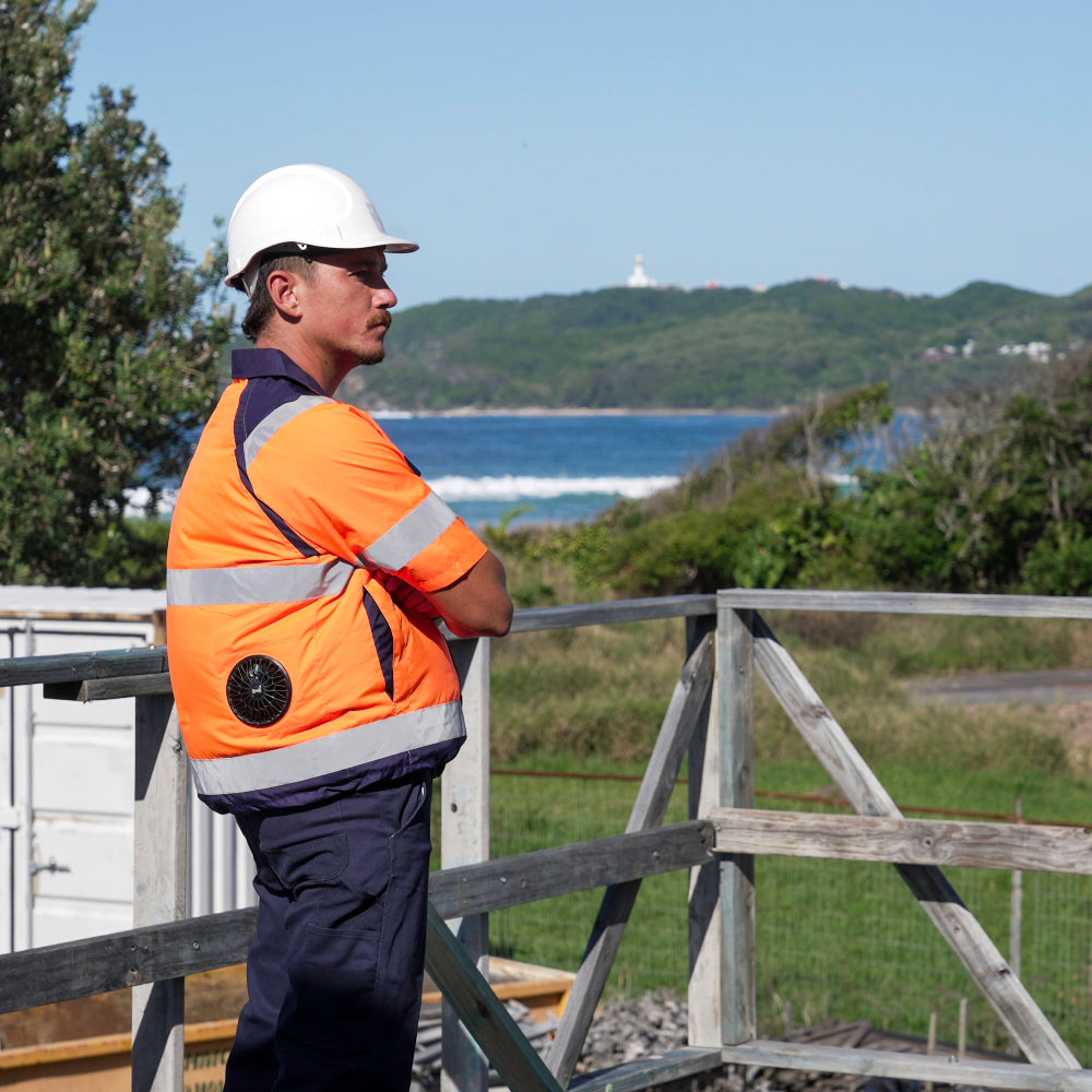 Person in safety gear standing on a wooden platform with a scenic background wearing a hi vis high visibility fan cooled jacket or ac wear