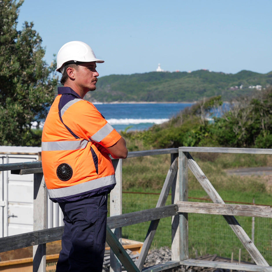 Person in safety gear standing on a wooden platform with a scenic background wearing a hi vis high visibility fan cooled jacket or ac wear