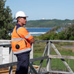 Person in safety gear standing on a wooden platform with a scenic background wearing a hi vis high visibility fan cooled jacket or ac wear